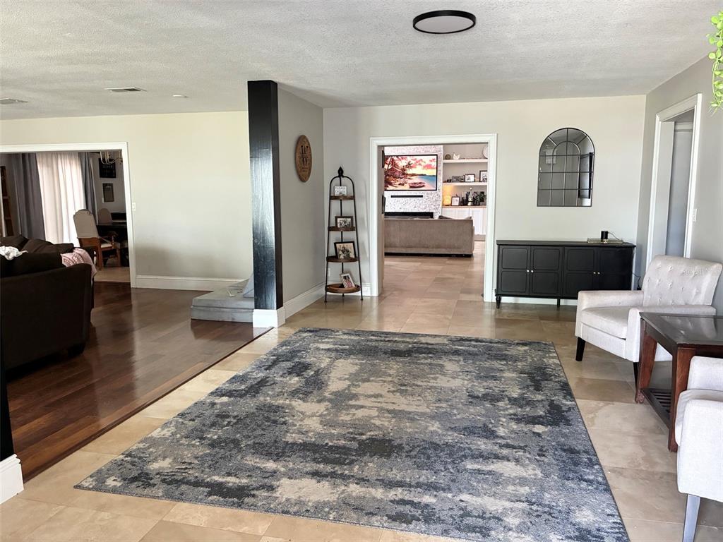 A living area features tile flooring, a large area rug, and a black accent pillar — 12305 LEANNE DRIVE, DADE CITY, FL