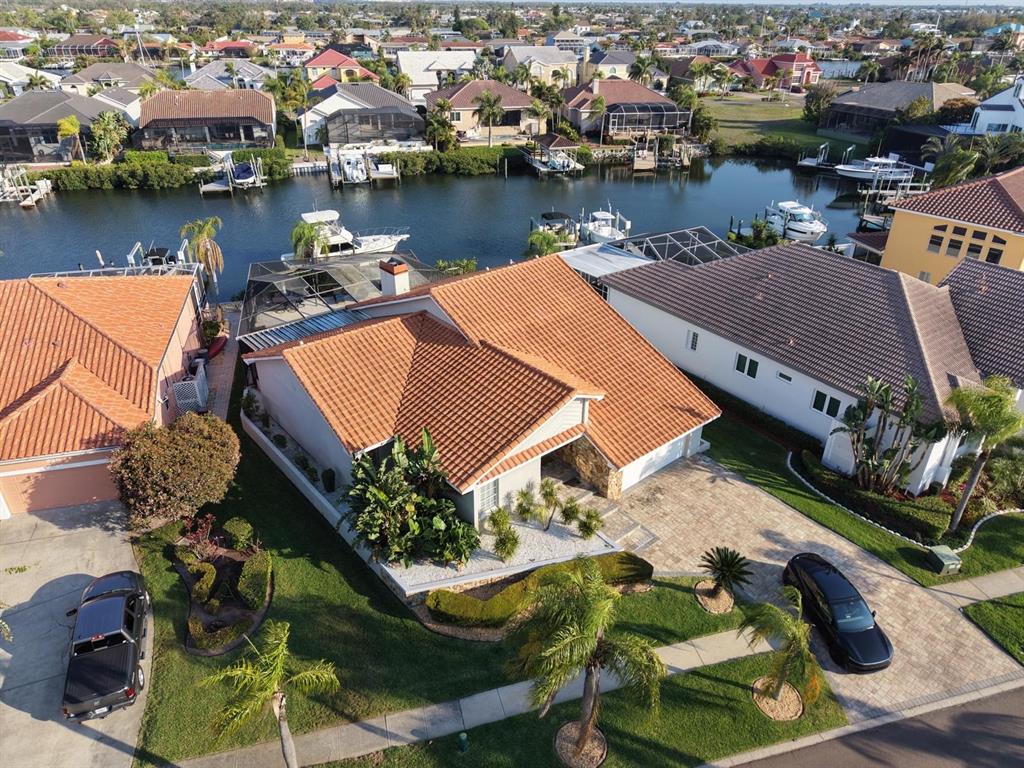 An aerial view shows a house with a terracotta tile roof, driveway, and canal access — 930 SYMPHONY ISLES BOULEVARD, APOLLO BEACH, FL