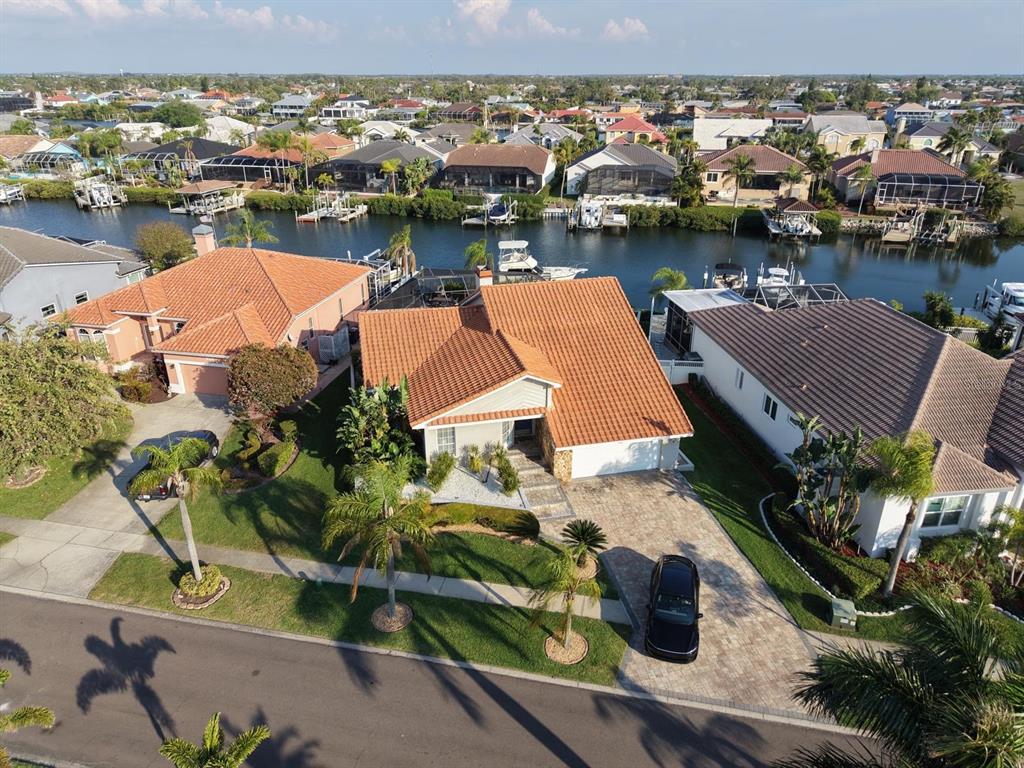 An aerial view shows a suburban house with a terracotta roof, driveway, and canal access — 930 SYMPHONY ISLES BOULEVARD, APOLLO BEACH, FL