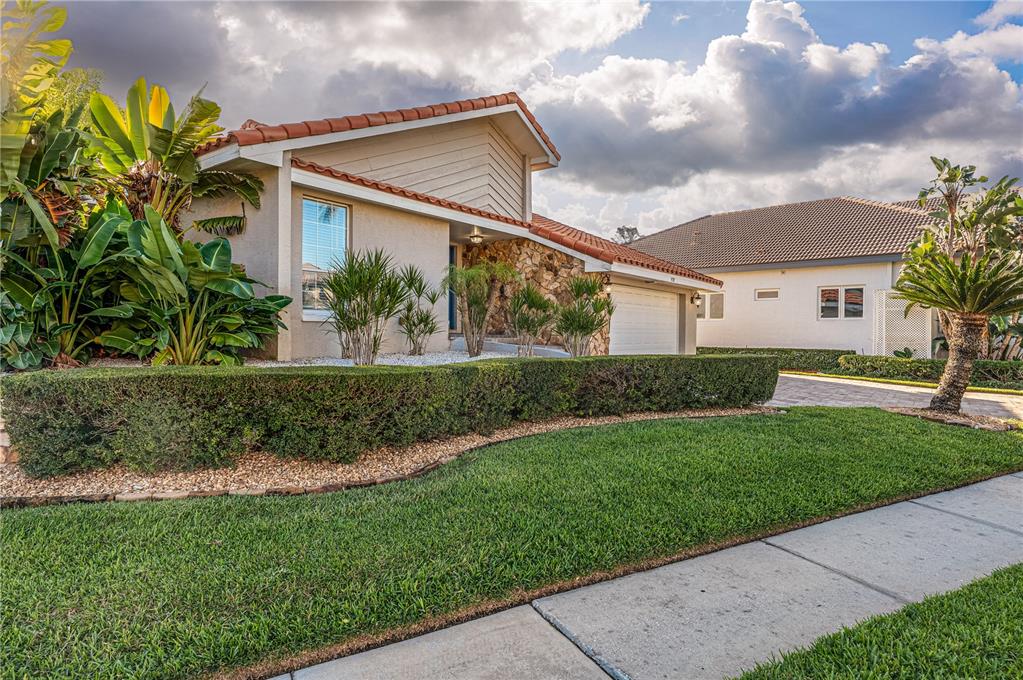 A single-story house with a stone facade, tile roof, and manicured hedge in the front yard — 930 SYMPHONY ISLES BOULEVARD, APOLLO BEACH, FL