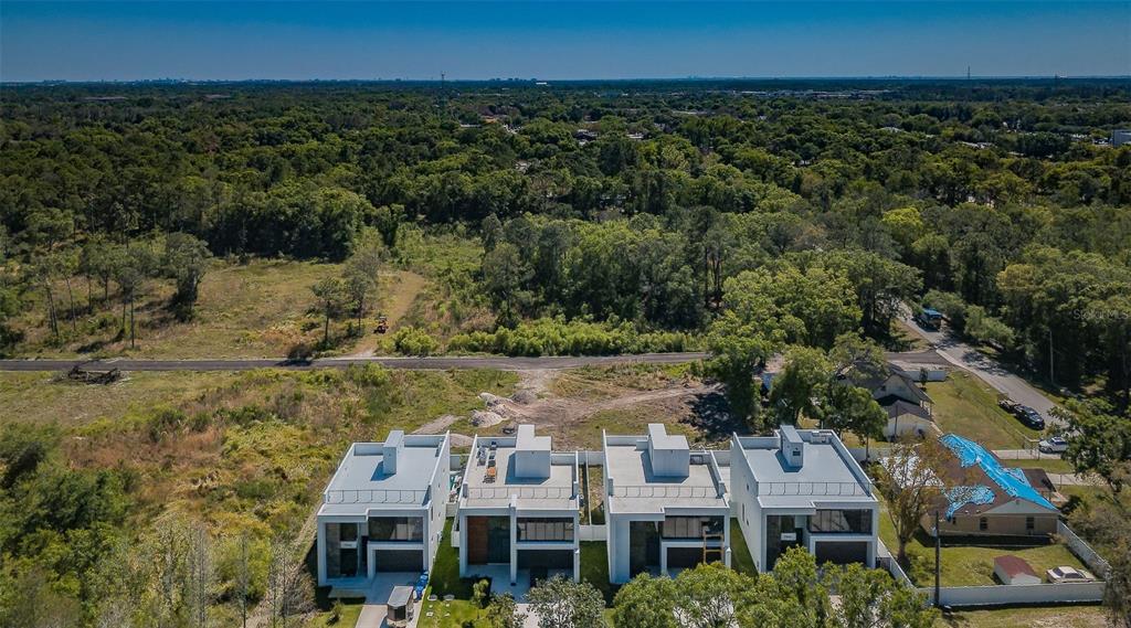 An aerial view shows a row of modern white townhouses next to a wooded area — 110 SKYTRAIL, TAMPA, FL