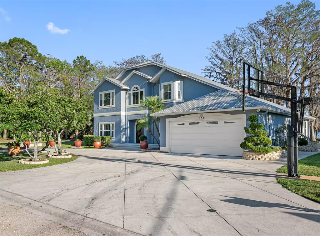 A two-story blue house with a metal roof, a white garage door, and a basketball hoop — 151 LAKESIDE DRIVE, SANFORD, FL