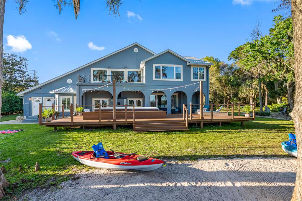 A blue two-story house features a large wooden deck with a hot tub and kayak — 151 LAKESIDE DRIVE, SANFORD, FL