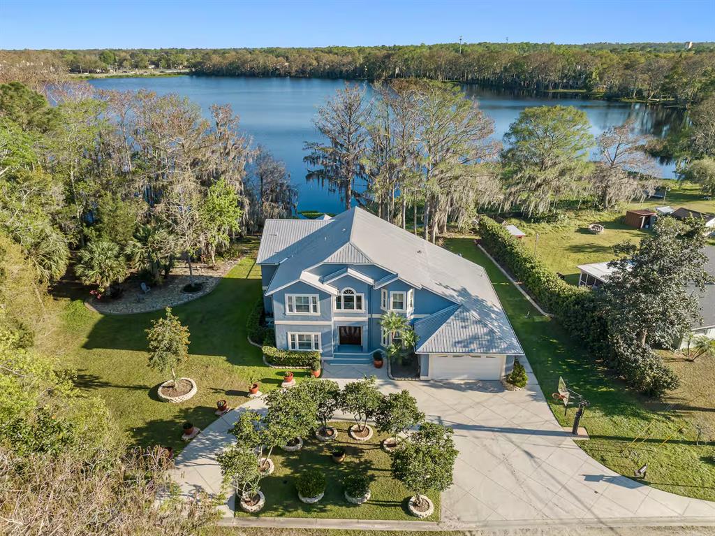 An aerial view of a blue two-story house with a metal roof near a lake — 151 LAKESIDE DRIVE, SANFORD, FL