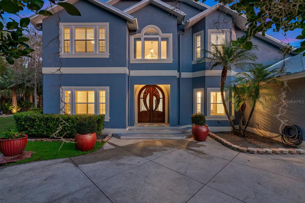 A two-story blue house with a concrete driveway, arched wooden front doors, and red planters — 151 LAKESIDE DRIVE, SANFORD, FL