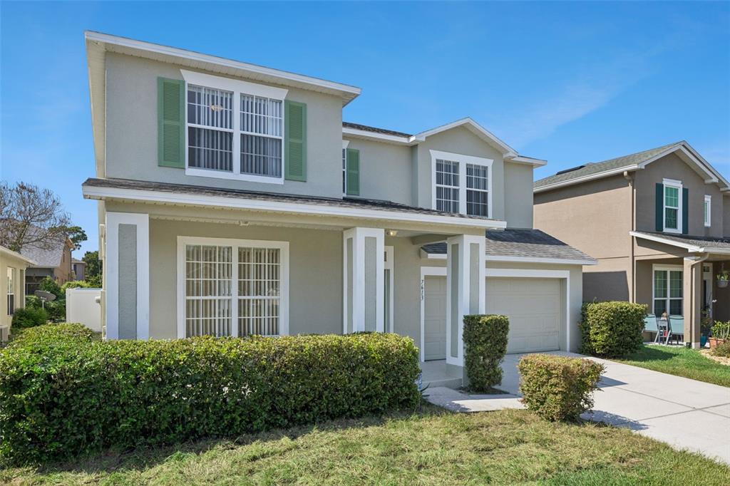 A two-story suburban house with a beige stucco exterior, green shutters, and a front hedge — 7613 BEAR CLAW RUN, ORLANDO, FL