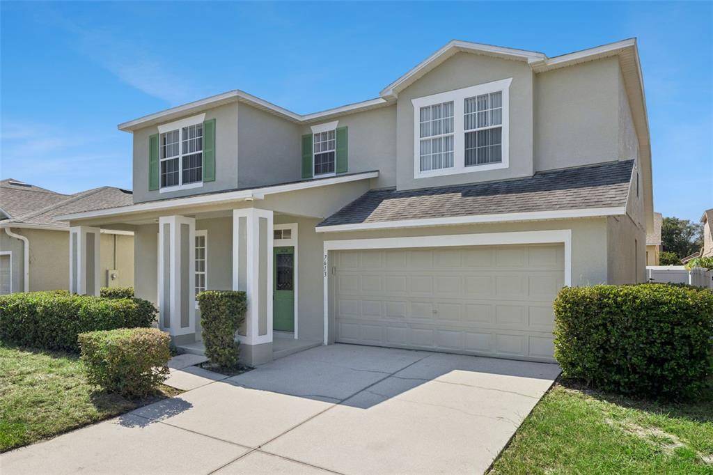 A two-story house with a beige stucco exterior, green shutters, and a two-car garage — 7613 BEAR CLAW RUN, ORLANDO, FL