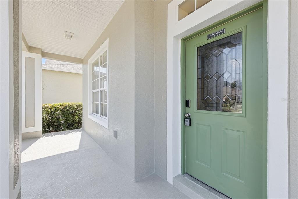 A covered porch features a light green front door with a decorative glass window — 7613 BEAR CLAW RUN, ORLANDO, FL