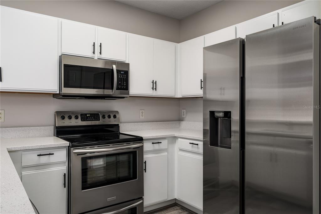 A kitchen features white cabinets, stainless steel appliances, and light-colored countertops — 6213 OSPREY LAKE CIRCLE, RIVERVIEW, FL