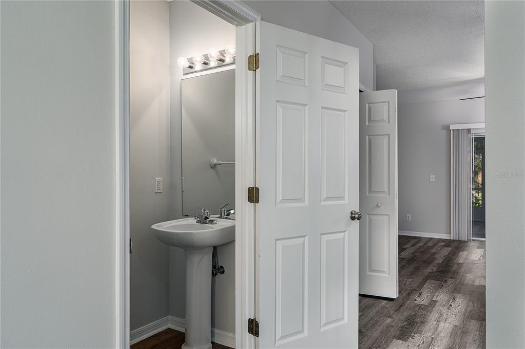 A small bathroom with a pedestal sink and mirror opens into a living area — 6213 OSPREY LAKE CIRCLE, RIVERVIEW, FL