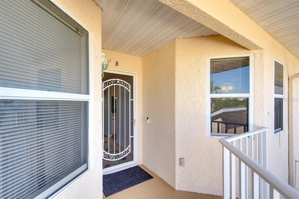 An exterior view of a residential entryway with a white screen door labeled B — 2608 WATERFORD WAY UNIT B, PALMETTO, FL