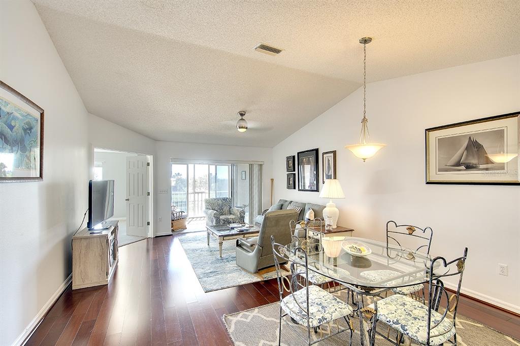 A living and dining area with hardwood floors, a glass table, and a sliding glass door — 2608 WATERFORD WAY UNIT B, PALMETTO, FL