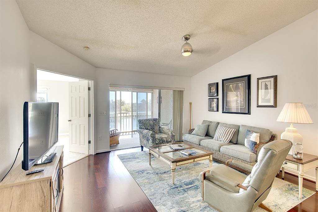 A living room features a sofa, armchair, coffee table, and a sliding door to a balcony — 2608 WATERFORD WAY UNIT B, PALMETTO, FL