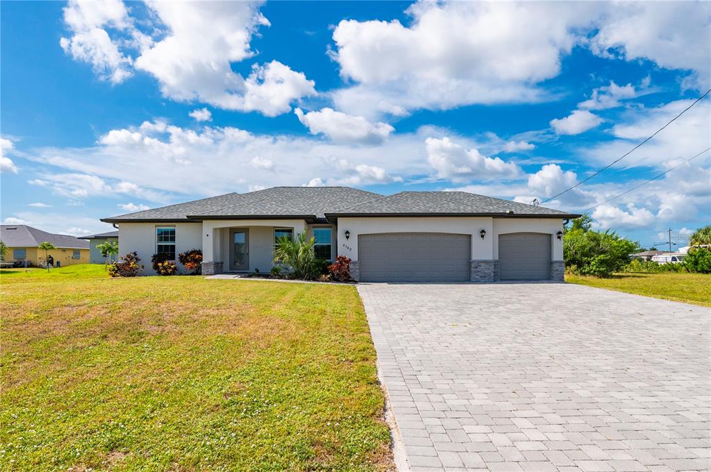 A single-story house with a gray shingled roof, white stucco walls, and a paved driveway — 4302 NW 32ND STREET, CAPE CORAL, FL