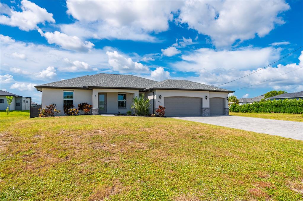 A single-story house with a gray roof, beige stucco exterior, and a three-car garage — 4302 NW 32ND STREET, CAPE CORAL, FL