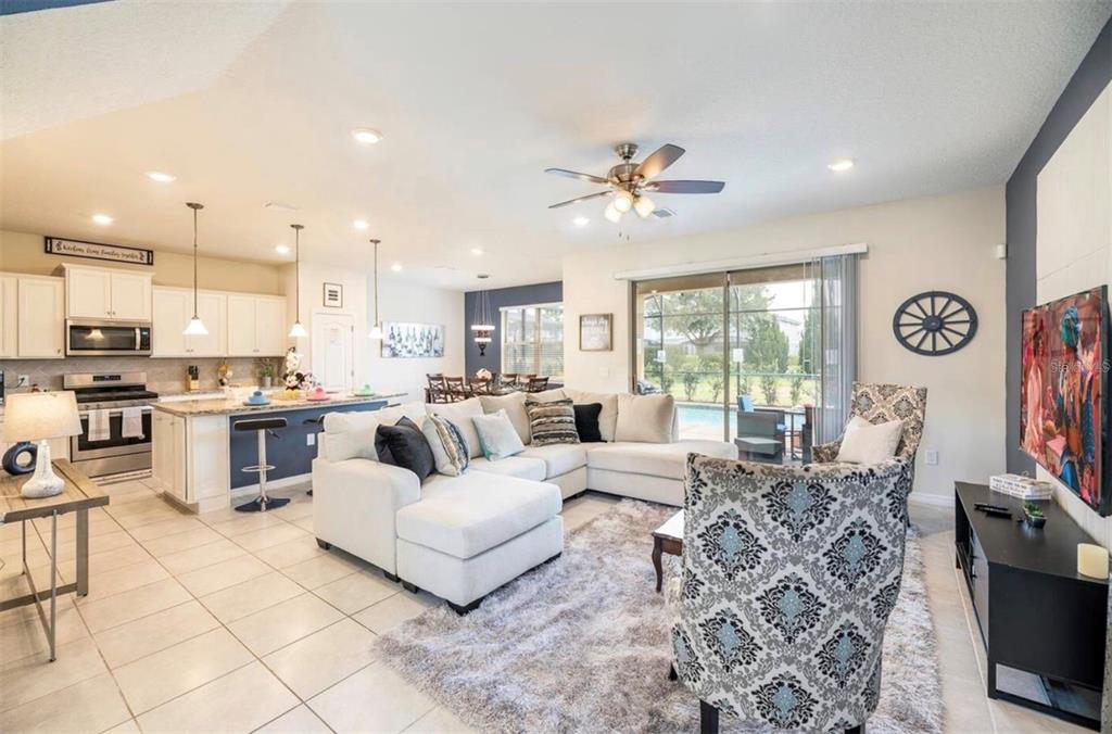 An open-concept living room and kitchen featuring a white sectional sofa and tile flooring — 5533 MISTY OAK CIRCLE, DAVENPORT, FL
