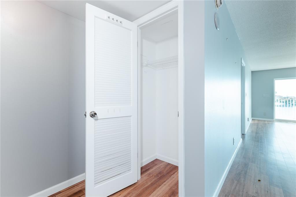 A white louvered closet door stands open, revealing a small storage space with wire shelving — 400 64TH AVENUE UNIT 305, ST PETE BEACH, FL