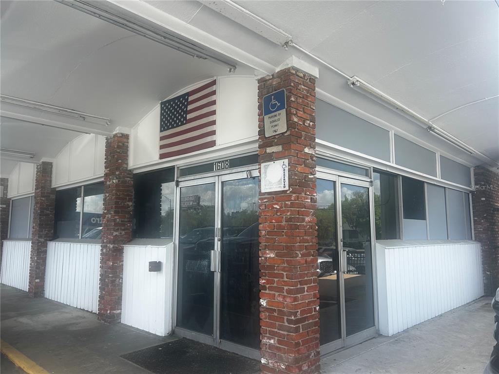 The exterior of a commercial building features brick columns, glass doors, and an American flag — 1610 S PINE AVENUE, OCALA, FL