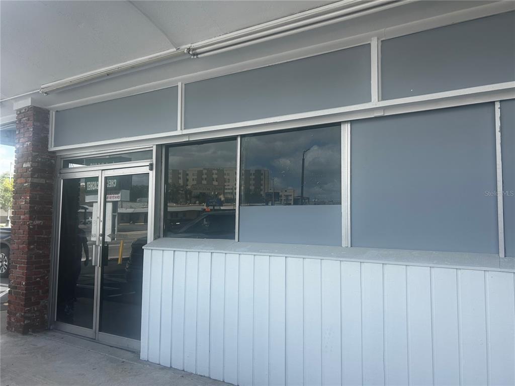 The exterior of a commercial building features a glass door, large windows, and white siding — 1610 S PINE AVENUE, OCALA, FL