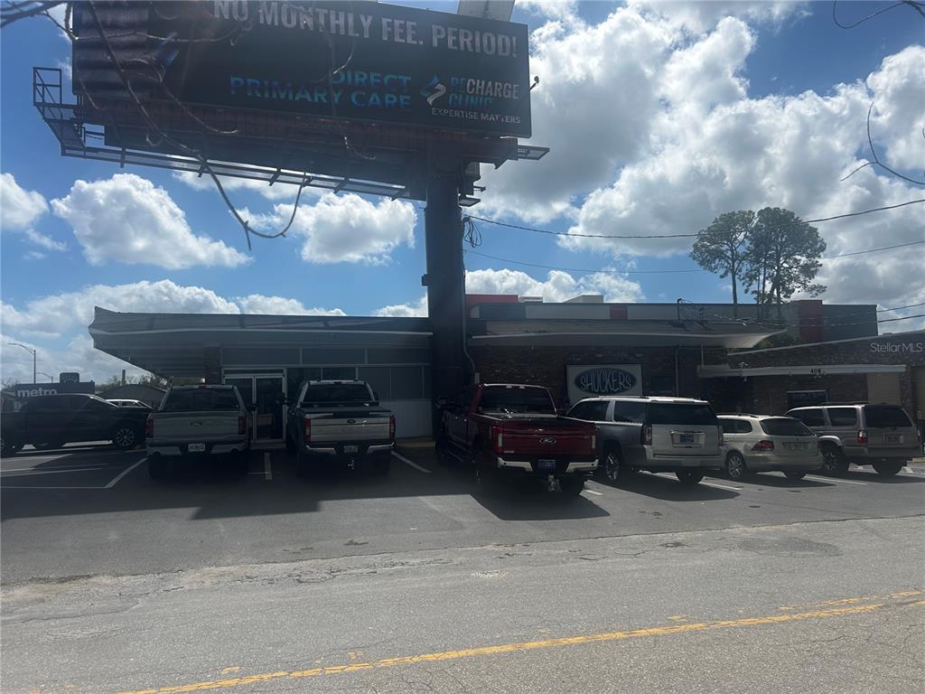 A commercial building with a billboard above and several parked vehicles in the front lot — 1610 S PINE AVENUE, OCALA, FL