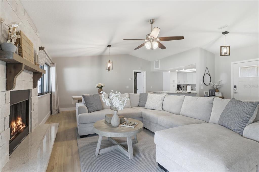 A living room features a stone fireplace, a large sectional sofa, and a ceiling fan — 11271 W CORAL COURT, CRYSTAL RIVER, FL