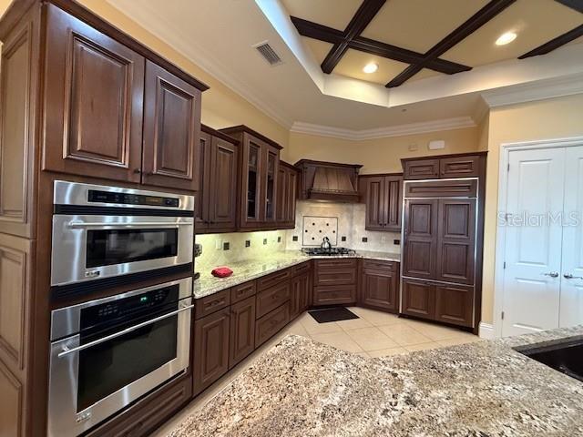 A kitchen features dark wood cabinetry, stainless steel double ovens, and granite countertops — 5508 SUMMIT POINTE CIRCLE UNIT 104, BRADENTON, FL