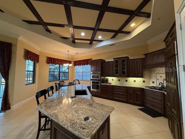 A kitchen features dark wood cabinetry, a large granite island, and a coffered ceiling — 5508 SUMMIT POINTE CIRCLE UNIT 104, BRADENTON, FL