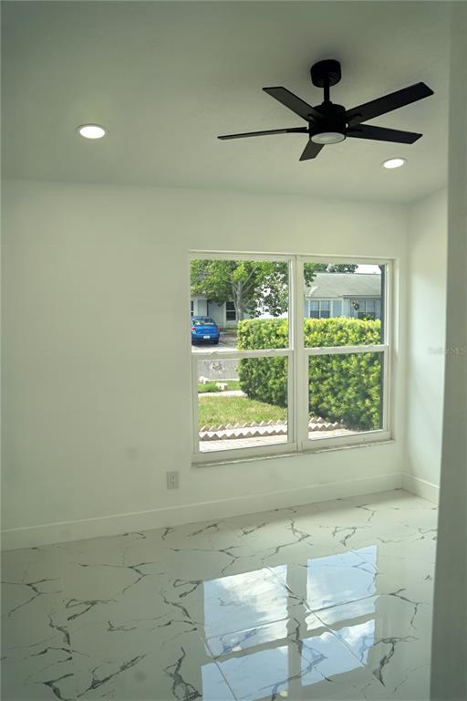 A room with white walls, a black ceiling fan, and white marble-patterned tile flooring — 9224 CAMINO VILLA BOULEVARD, TAMPA, FL