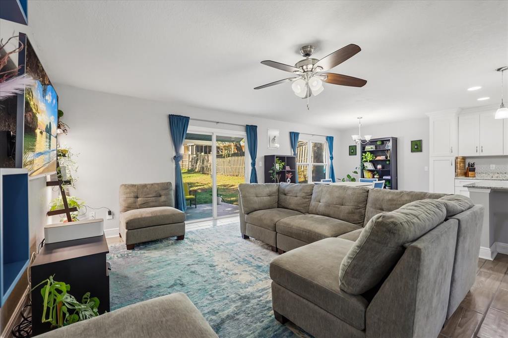 A living room with a large gray sectional, area rug, and sliding glass patio doors — 524 E HILLCREST STREET, ALTAMONTE SPRINGS, FL