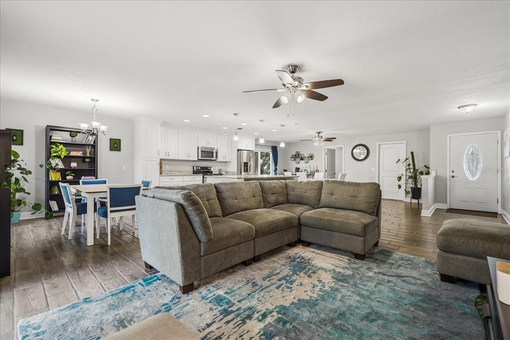 An open-concept living room and kitchen feature gray tile flooring, a sectional sofa, and white cabinetry — 524 E HILLCREST STREET, ALTAMONTE SPRINGS, FL