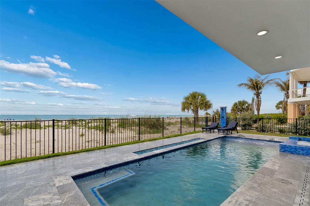 A swimming pool sits on a patio overlooking a sandy beach and the ocean — 930 ELDORADO AVENUE, CLEARWATER BEACH, FL