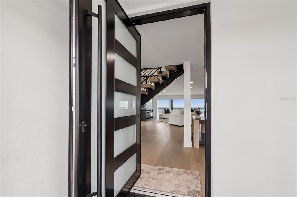 A modern front door opens into a bright living area with a floating staircase — 930 ELDORADO AVENUE, CLEARWATER BEACH, FL