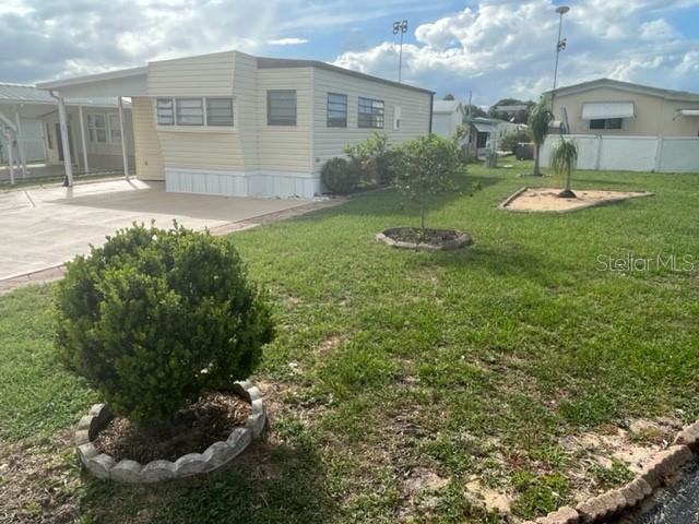 A light-colored mobile home features a carport and a landscaped yard with small trees — 251 PATTERSON ROAD UNIT C44, HAINES CITY, FL