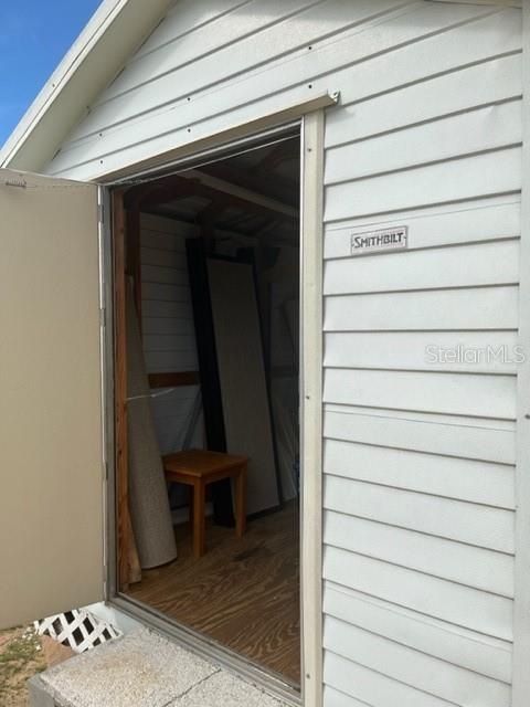 A white vinyl-sided shed with an open door revealing a small wooden table inside — 251 PATTERSON ROAD UNIT C44, HAINES CITY, FL