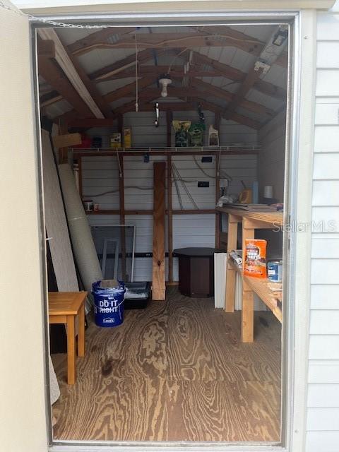 A view into a wooden storage shed with exposed rafters, shelving, and a plywood floor — 251 PATTERSON ROAD UNIT C44, HAINES CITY, FL