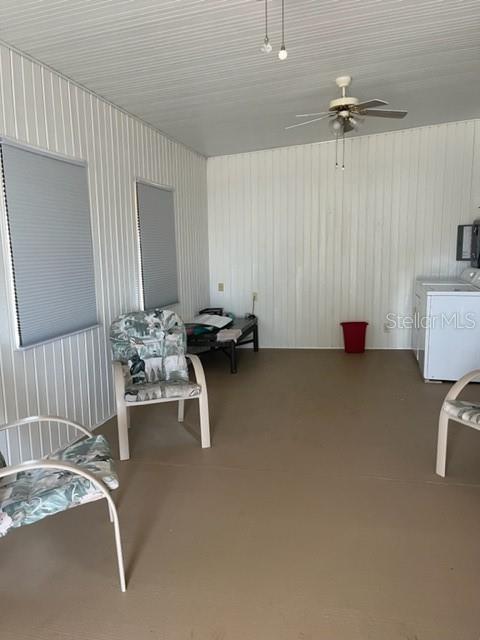 A sunroom with white paneled walls, a ceiling fan, two chairs, and a laundry appliance — 251 PATTERSON ROAD UNIT C44, HAINES CITY, FL