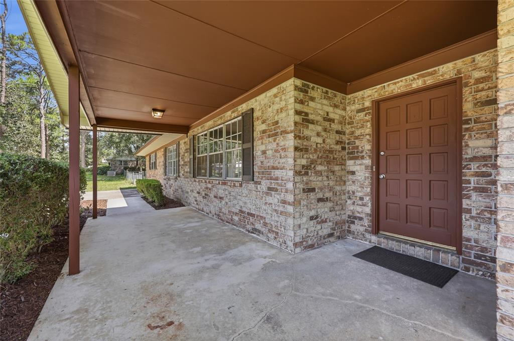A brick house exterior features a covered concrete porch and a brown paneled front door — 167 SW THURMAN TERRACE, LAKE CITY, FL