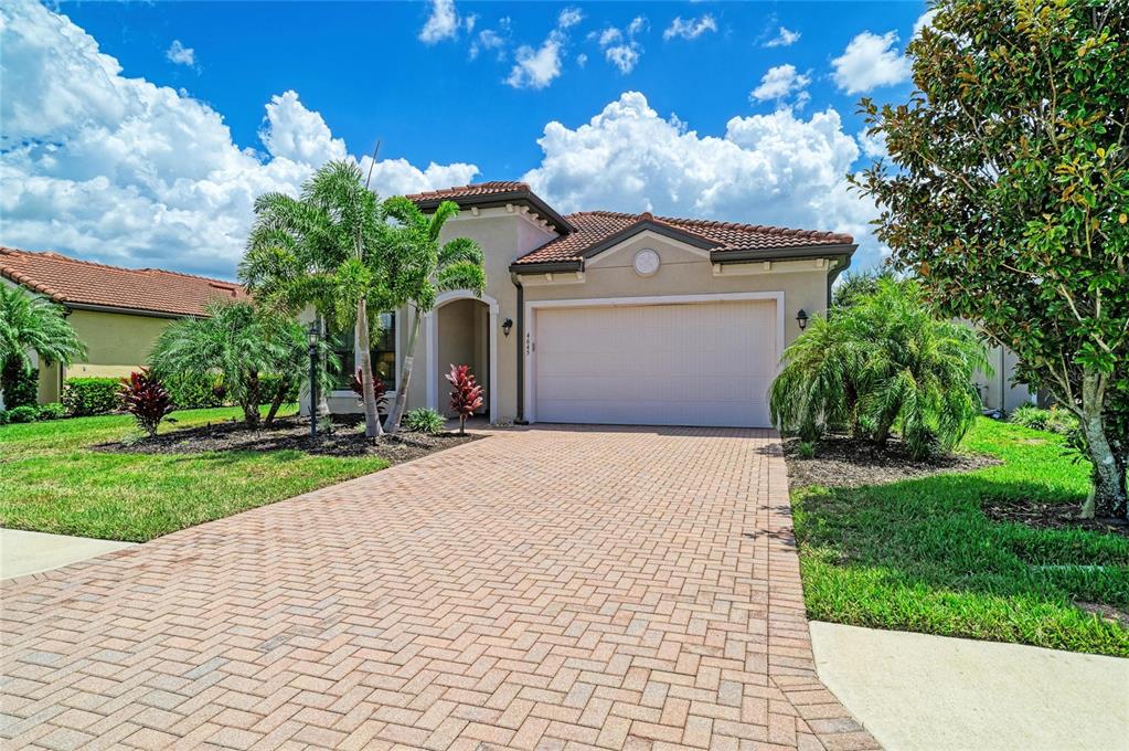 A single-story house with a tiled roof, a brick driveway, and palm trees in front — 4645 ROYAL DORNOCH CIRCLE, BRADENTON, FL