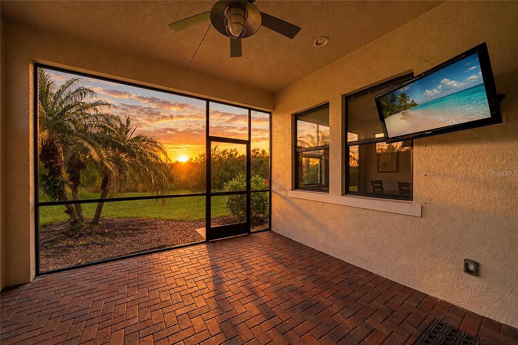 A covered patio with brick flooring, a ceiling fan, and a view of a sunset — 4645 ROYAL DORNOCH CIRCLE, BRADENTON, FL
