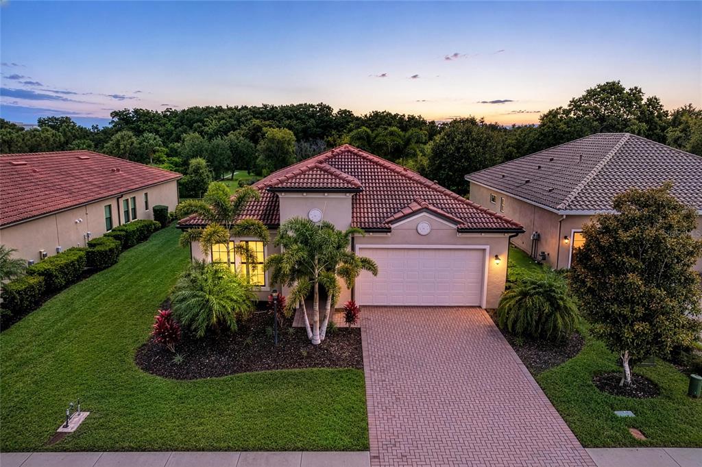 An elevated exterior view of a single-story house with a tiled roof and paved driveway — 4645 ROYAL DORNOCH CIRCLE, BRADENTON, FL