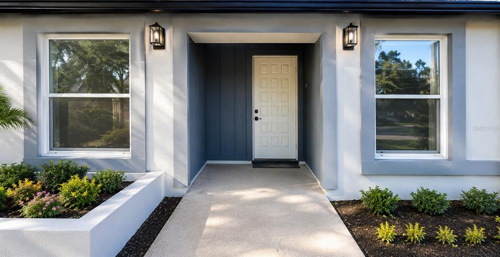The exterior of a house features a white front door, two windows, and landscaped beds — 7924 GUARDSMEN STREET, ORLANDO, FL