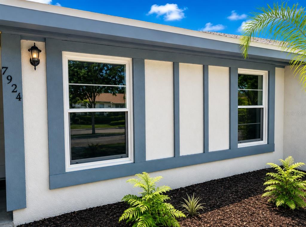 The exterior of a house features white stucco walls, blue trim, and two windows — 7924 GUARDSMEN STREET, ORLANDO, FL