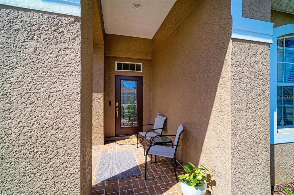 A covered entryway with a brown front door, two chairs, and a tiled floor — 1401 PINYON PINE DRIVE, SARASOTA, FL
