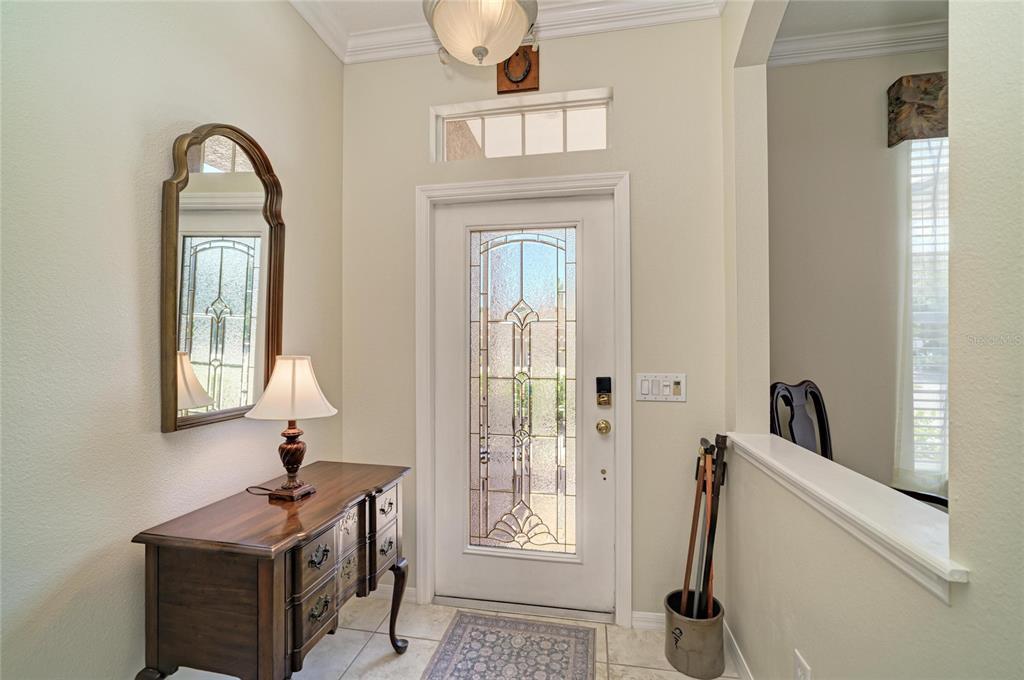 An entryway features a wood console table, a mirror, a glass-paneled front door, and tile flooring — 1401 PINYON PINE DRIVE, SARASOTA, FL
