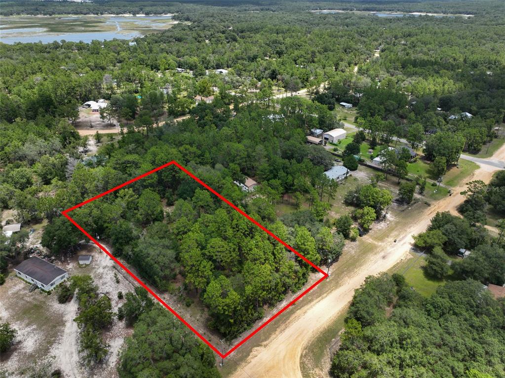 An aerial view shows a rectangular, tree-covered vacant lot outlined in red next to a road — 5630 LASSEN STREET, KEYSTONE HEIGHTS, FL