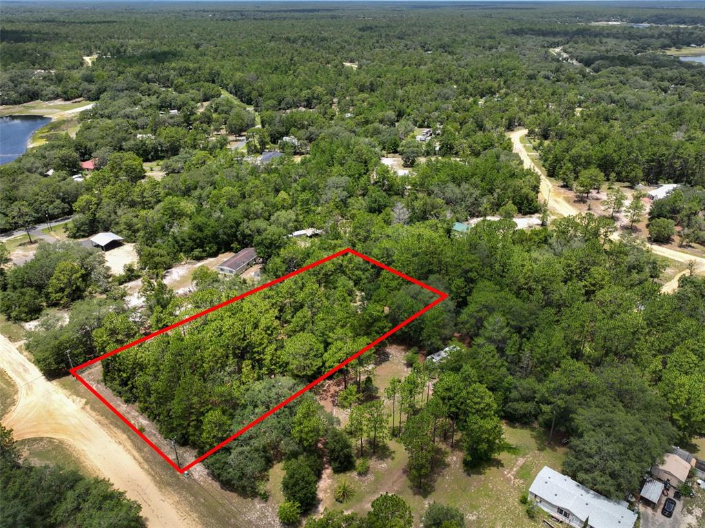 An aerial view shows a rectangular plot of land outlined in red amidst wooded surroundings — 5630 LASSEN STREET, KEYSTONE HEIGHTS, FL