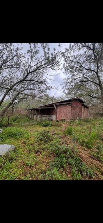 A weathered brick barn with a covered porch sits in a wooded, overgrown field — 20231 PAINTER PLACE PLACE, SPRING HILL, FL