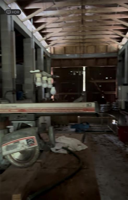 A workshop interior features a radial arm saw in the foreground and exposed wooden trusses — 20231 PAINTER PLACE PLACE, SPRING HILL, FL