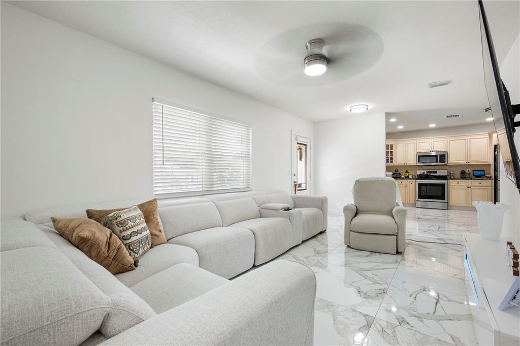 A living room with white marble floors, a large sectional sofa, and an open kitchen — 2811 W OHIO AVENUE, TAMPA, FL