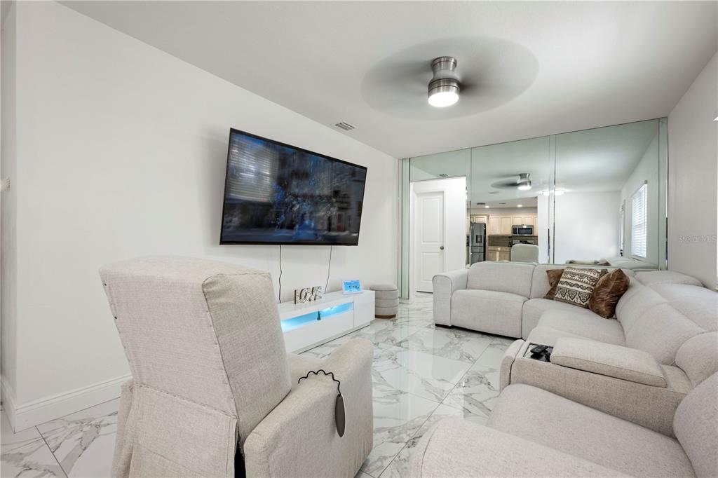 A living room features white marble floors, a wall-mounted television, and a large sectional sofa — 2811 W OHIO AVENUE, TAMPA, FL